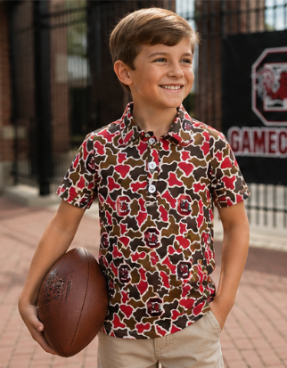 Young boy wearing a Gamecocks camouflage polo with khaki shorts on game day.