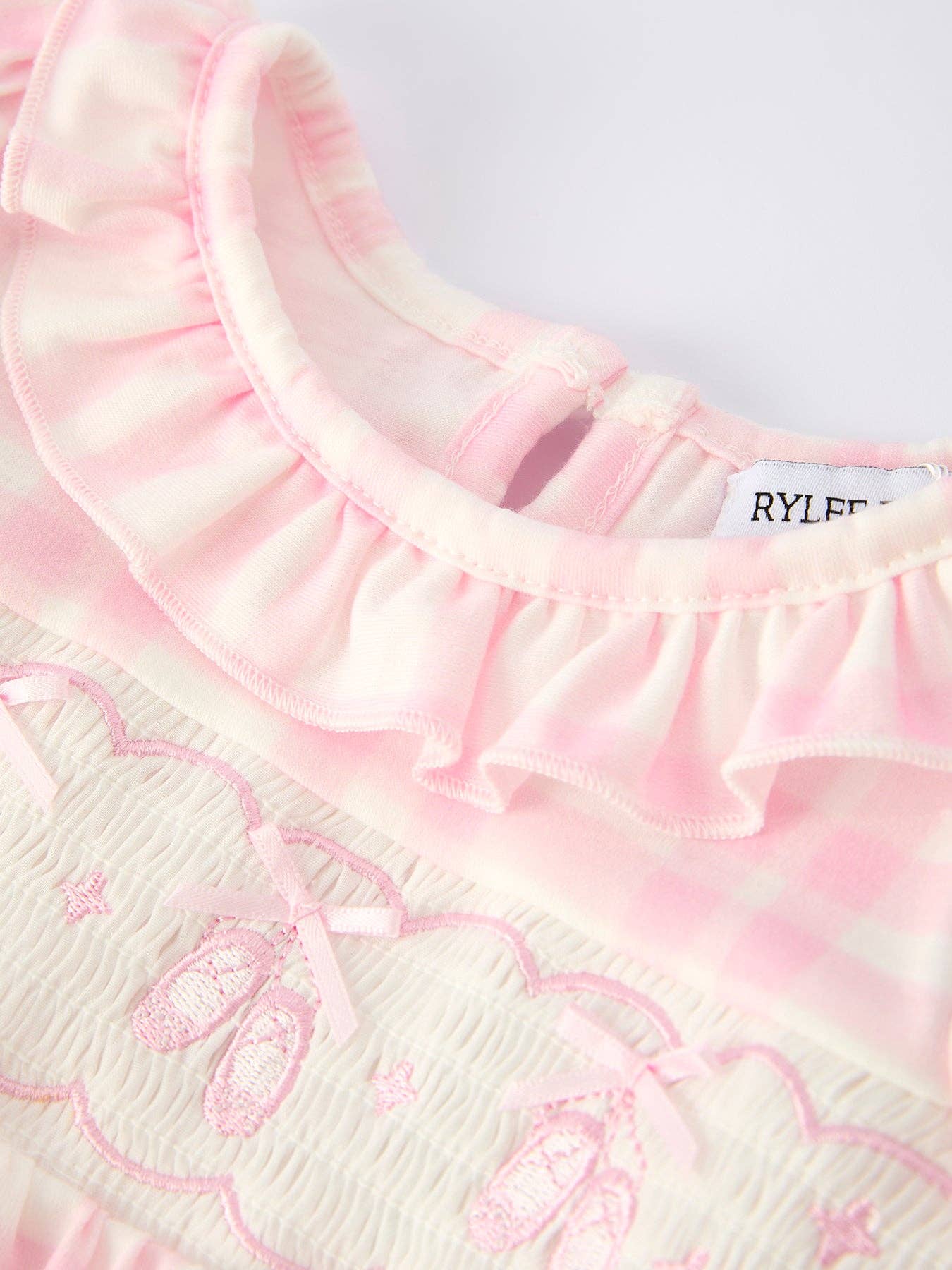 Close-up of a pink and white textured garment with ruffled collar and 'RYLEE' label.