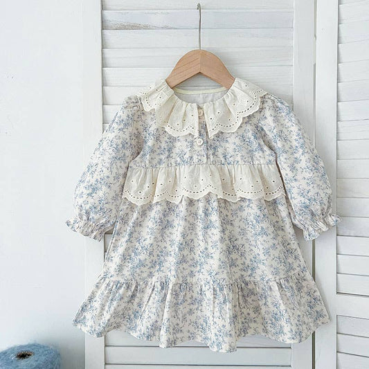 Floral dress with a white collar on a wooden hanger against a white wooden panel background