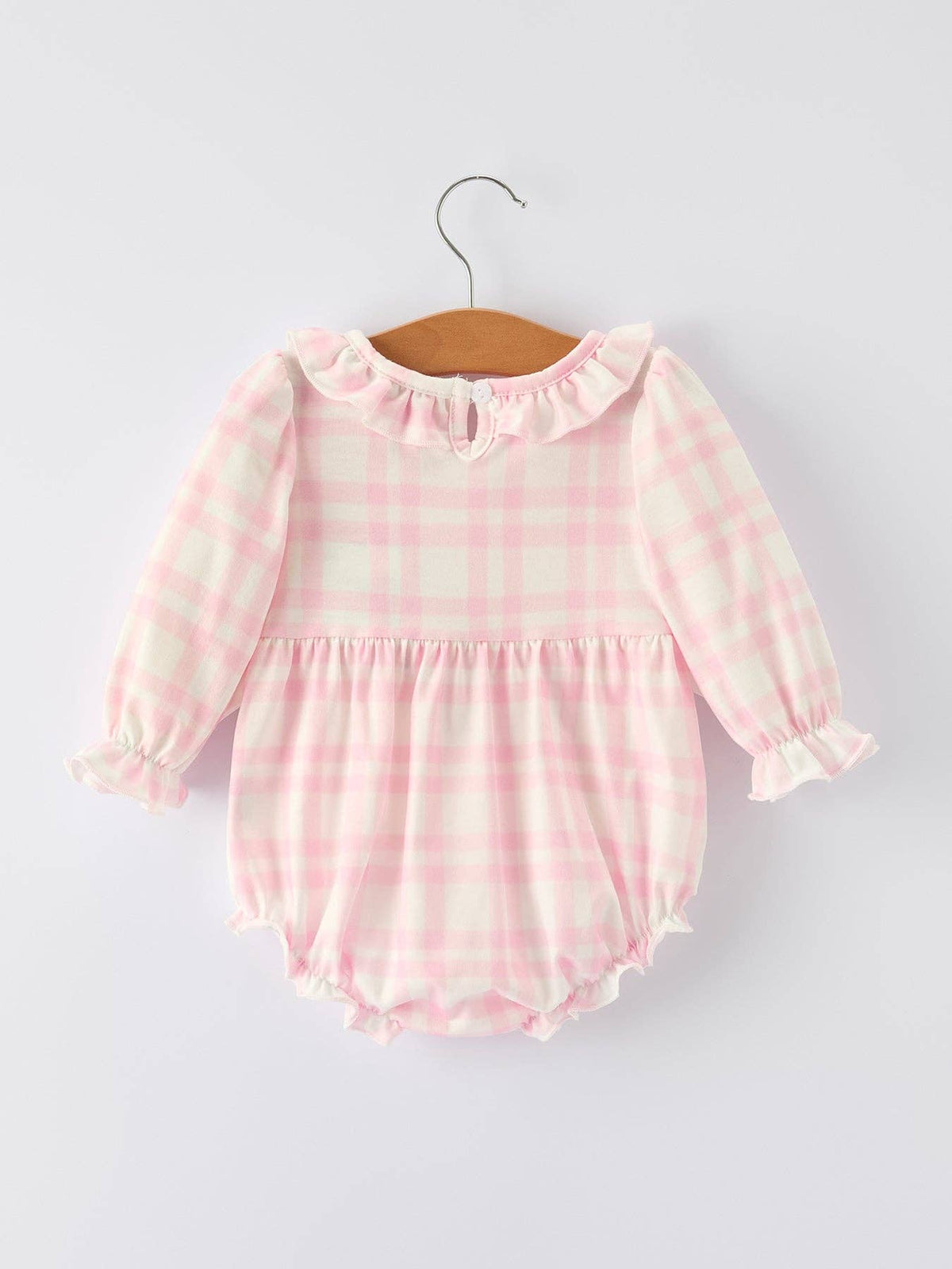 Pink and white checkered baby romper on a hanger against a light gray background