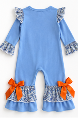 A light blue long-sleeve romper for toddlers, featuring ruffled sleeves and hem, orange bow accents at the bottom, and a blue-and-white floral patterned ruffle trim.