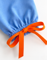 A close-up of a light blue fabric pouch or bag with a gathered elastic top and a bright orange ribbon tied in a bow, shown on a plain white background.