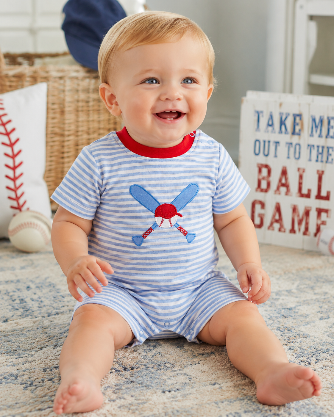 Baby boy wearing a blue stripe baseball appliqué romper at the baseball field.