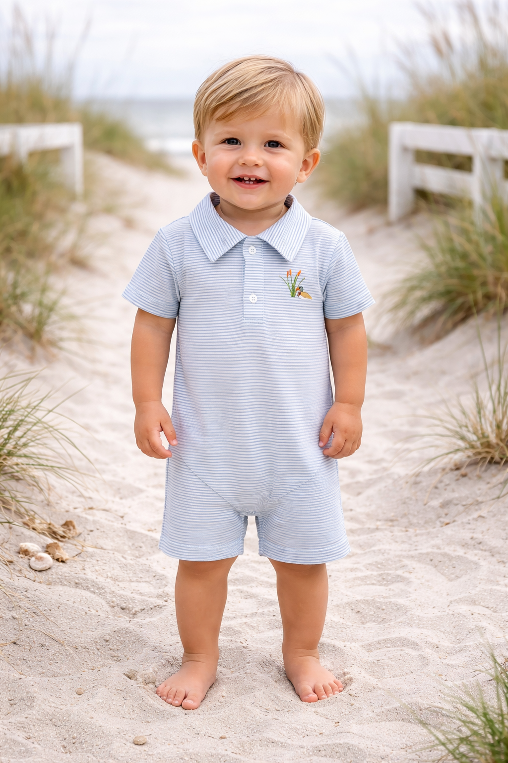 Baby boy wearing a blue stripe embroidered mallard shortall outdoors in classic Southern boutique style.