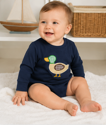 Baby boy wearing a navy mallard appliqué bubble romper at a fall family gathering.
