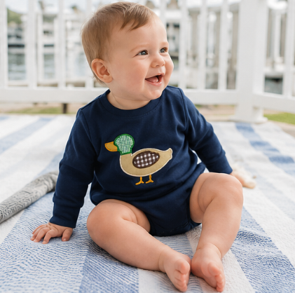 Little boy wearing a classic navy mallard appliqué bubble romper outdoors during autumn.